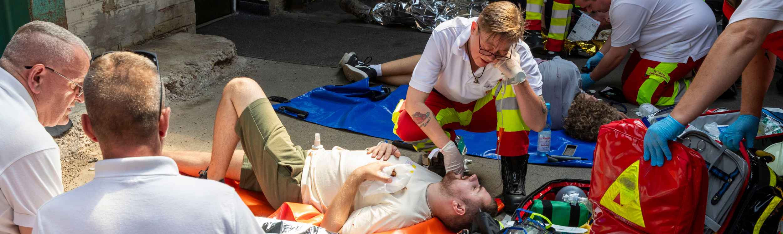 Einsatzkräfte aus dem Katastrophenschutz versorgen einen verletzten Mann, der auf einer Trage liegt.