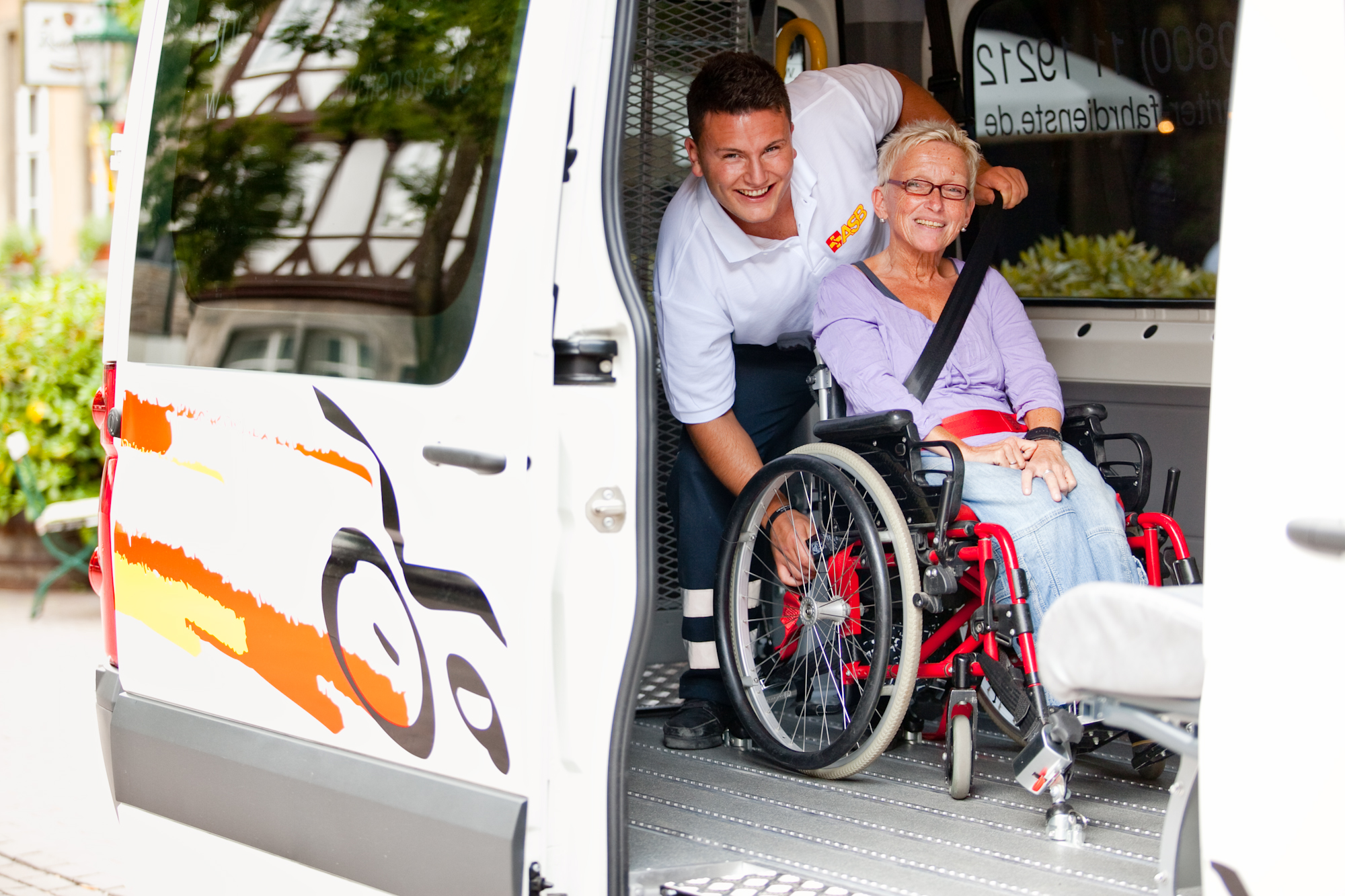 Betreuer des ASB und eine Frau im Rollstuhl in einem Transporter