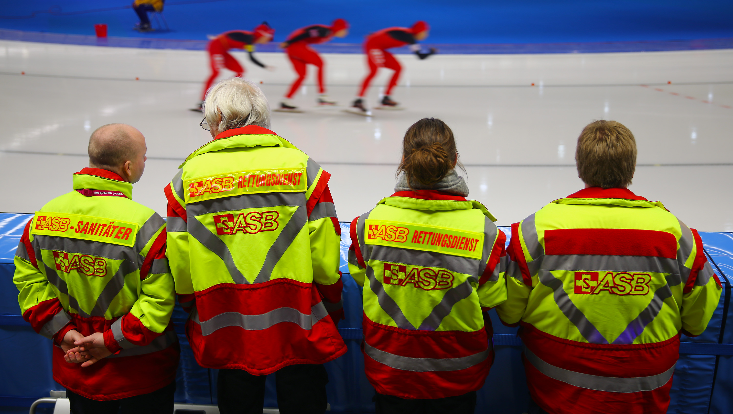 Vier Sanitäter des ASB blicken auf eine Eisrennbahn.