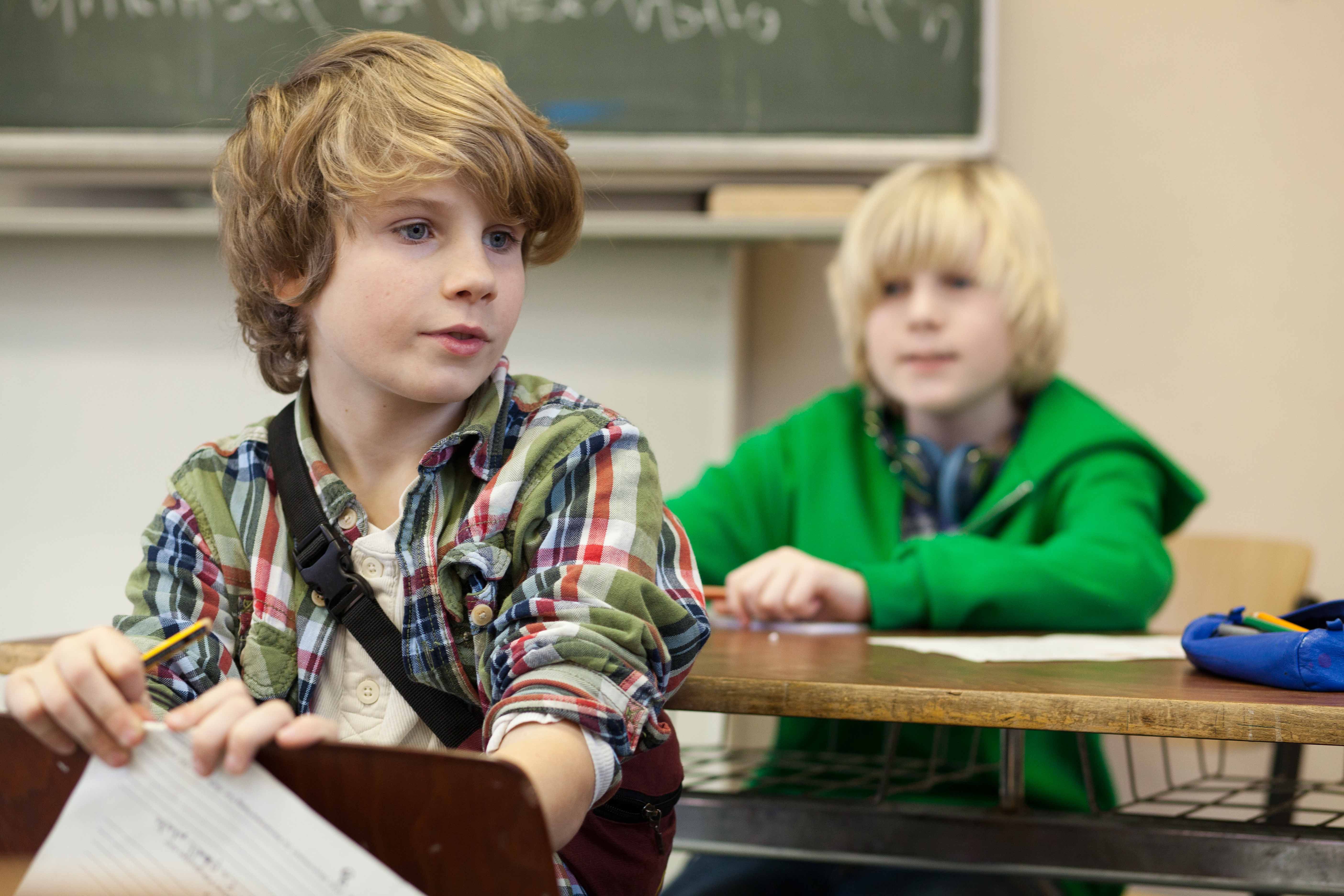 Zwei Kinder sitzen im Klassenzimmer an ihren Plätzen und  lernen.